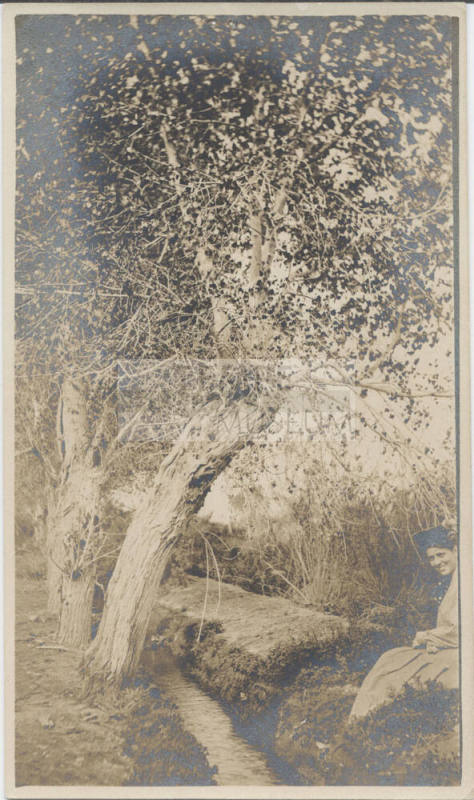 Woman Sitting by Small Irrigation Ditch