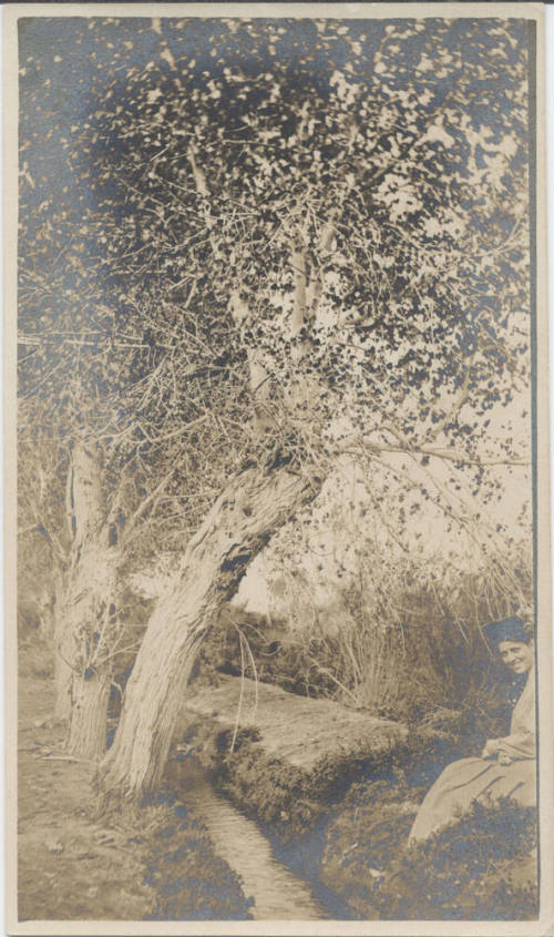 Woman Sitting by Small Irrigation Ditch