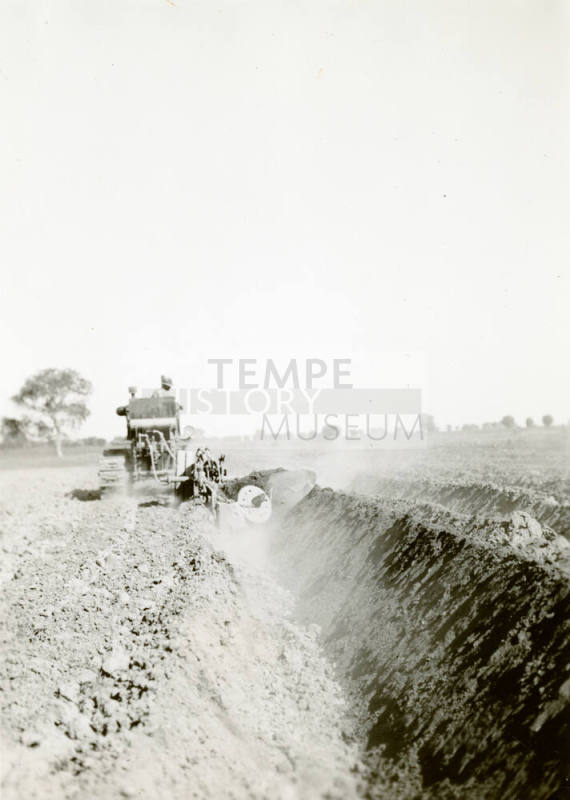 Rear View of Tractor Pulling Ditch Plow