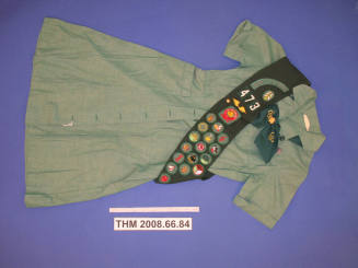 Girl Scout uniform with badge sash and tie
