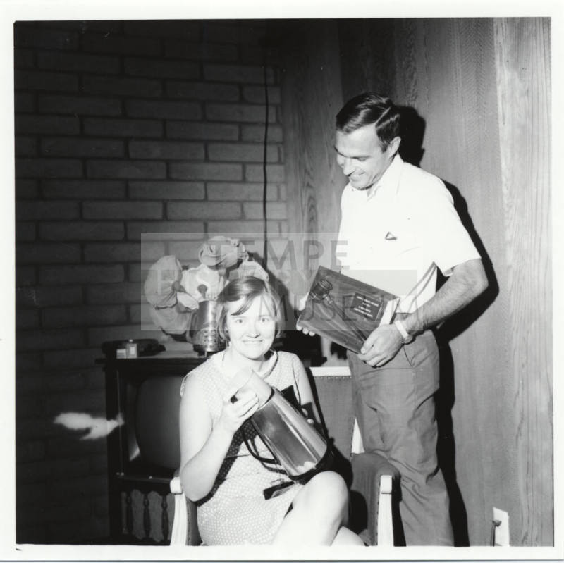 Man and Woman Posed with Plaque and Coffee Pot