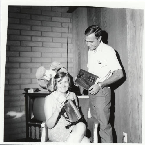Man and Woman Posed with Plaque and Coffee Pot