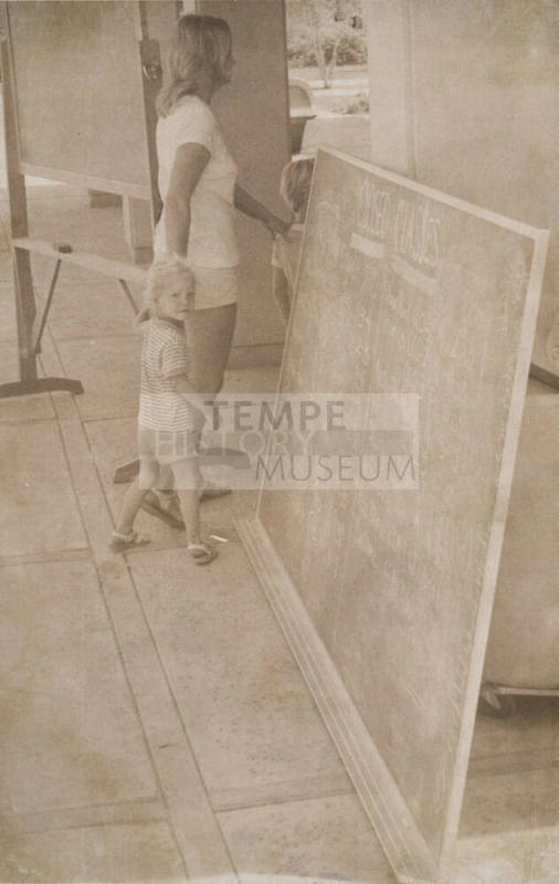 Woman and Children Pass Blackboard with "Closed Classes" Notification