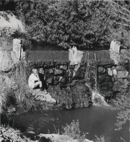 Young Boy Sitting Beside Waterfall and Stream in Moeur Park