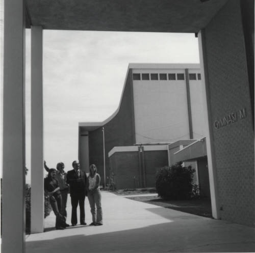 Four people standing near the doorway of a gymnasium, McClintock High School