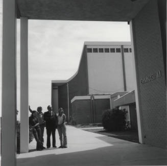 Four people standing near the doorway of a gymnasium, McClintock High School