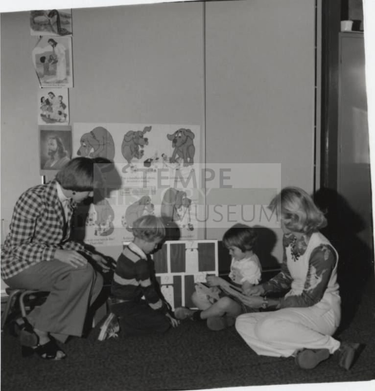 Two children and two women seated on the ground