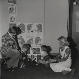 Two children and two women seated on the ground