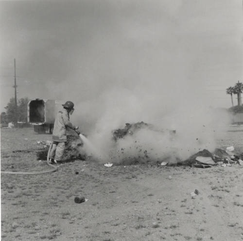 One Firemen with Hose & Smoldering Pile