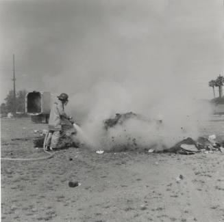One Firemen with Hose & Smoldering Pile