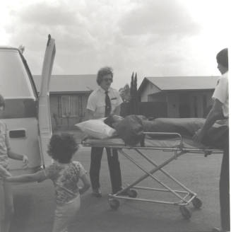 Unidentified Group - 2 uniformed men load individual on gurney into van