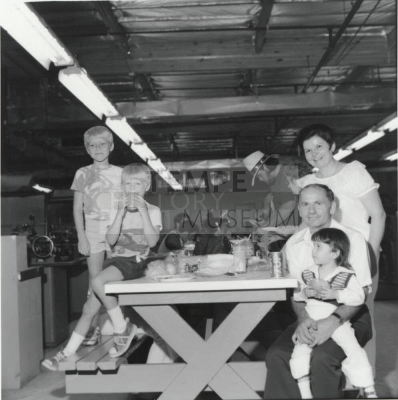 Three Kids and Two Adults Eating at an Indoor Picnic Table