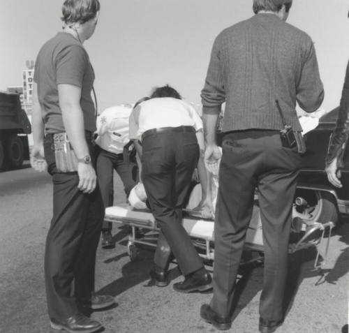 Paramedics loading traffic victim onto gurney.