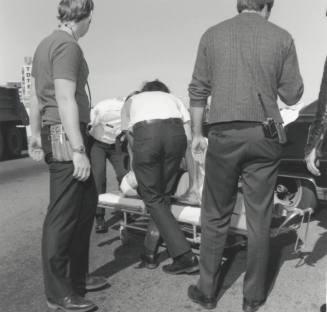Paramedics loading traffic victim onto gurney.