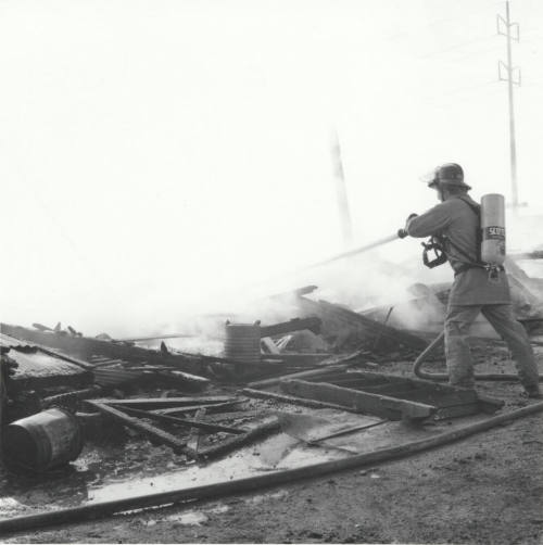 Firefighter Sprays Water On Smouldering Building