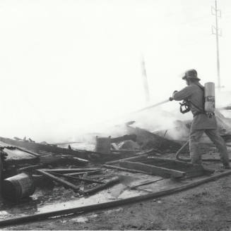 Firefighter Sprays Water On Smouldering Building