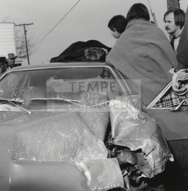 People gather around a wrecked car