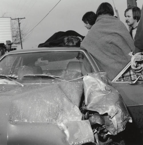 People gather around a wrecked car