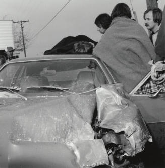 People gather around a wrecked car