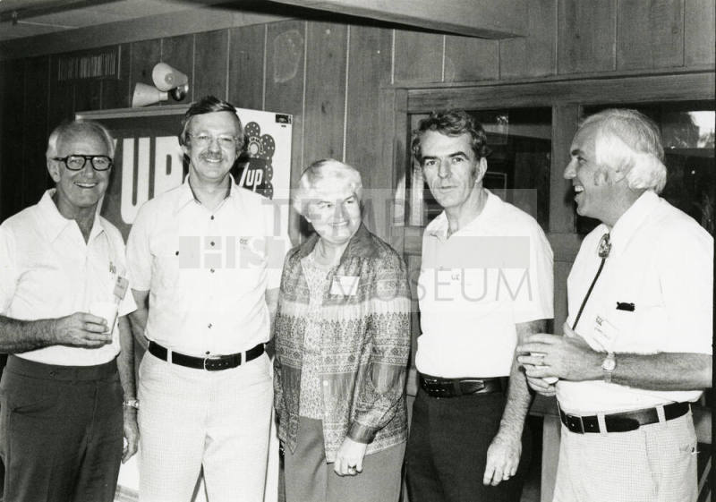 Four men and a woman at a soda dispenser.