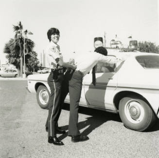 Unidentified Smiling Police Officer Handcuffs Suspect