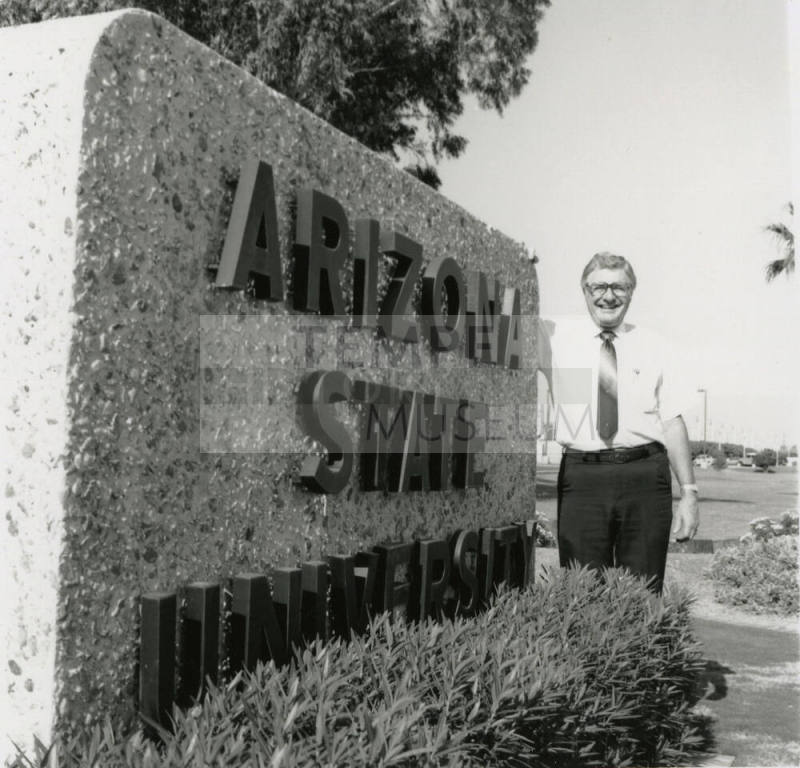 Unidentified man beside a large Arizona State University sign
