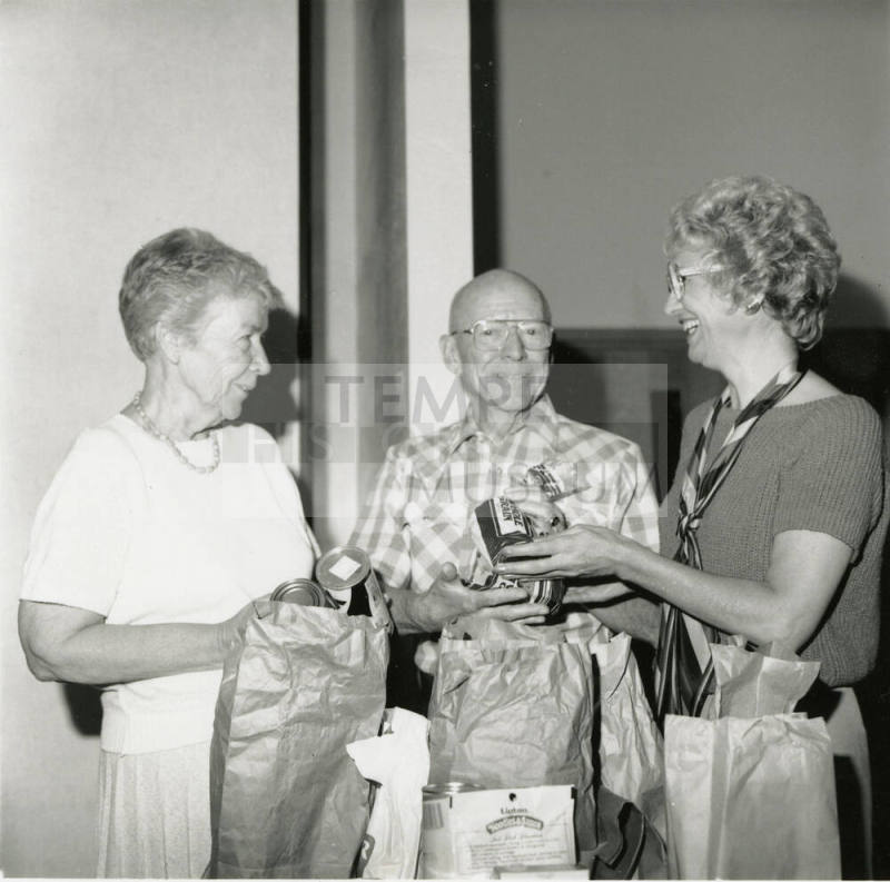 Three unidentified people with bags of groceries