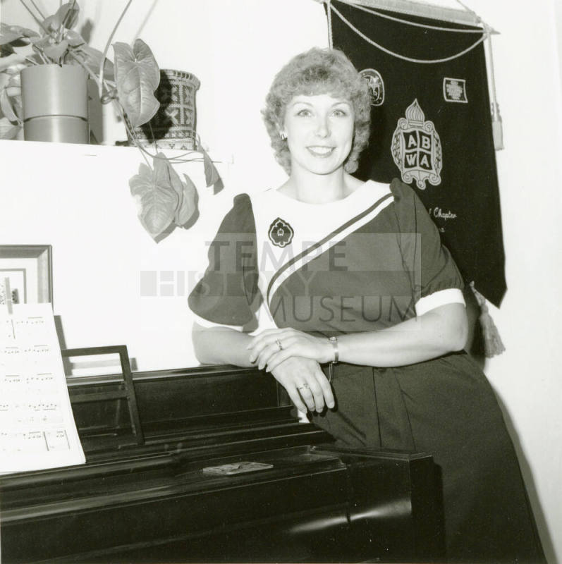 Unidentified woman leaning on a piano