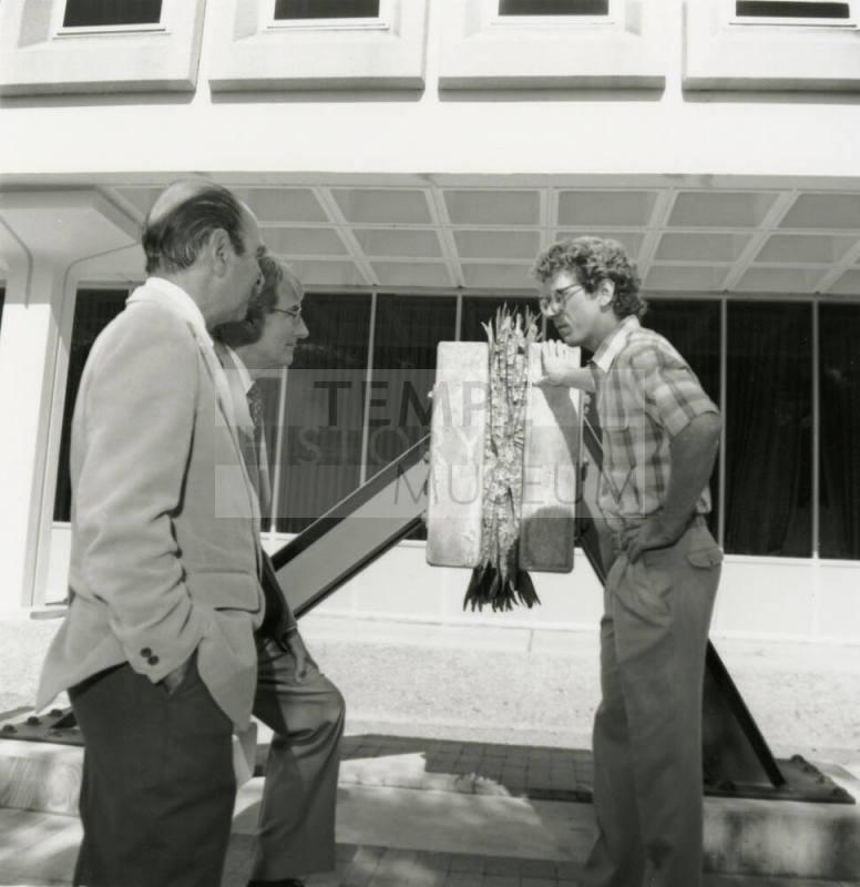 Three unidentified men chatting in front of a building