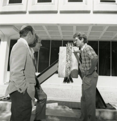 Three unidentified men chatting in front of a building