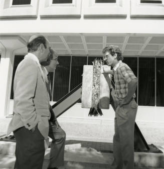 Three unidentified men chatting in front of a building
