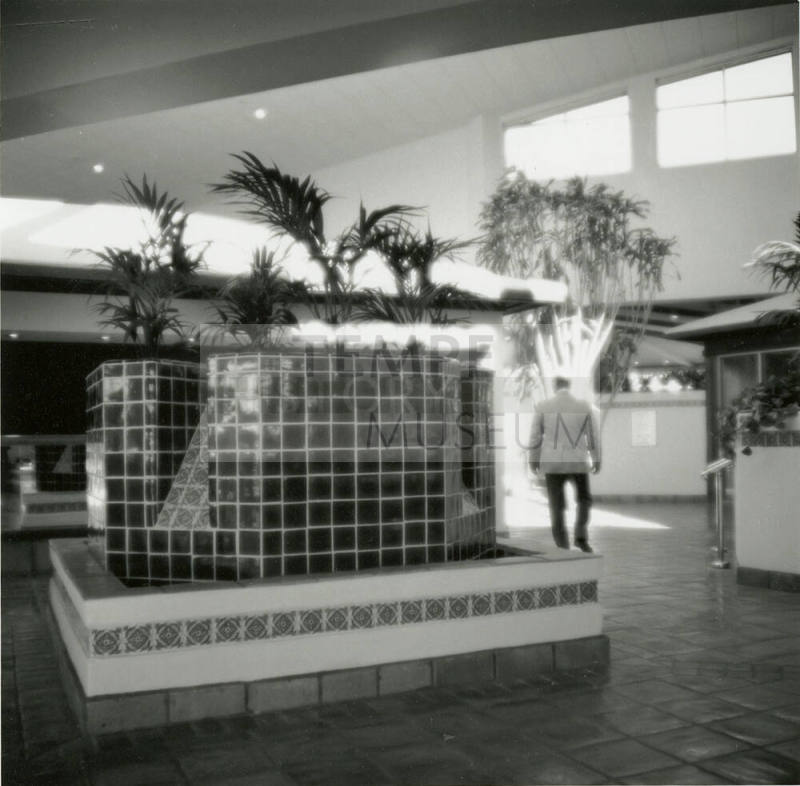 Man walking through interior of building with tile fountain