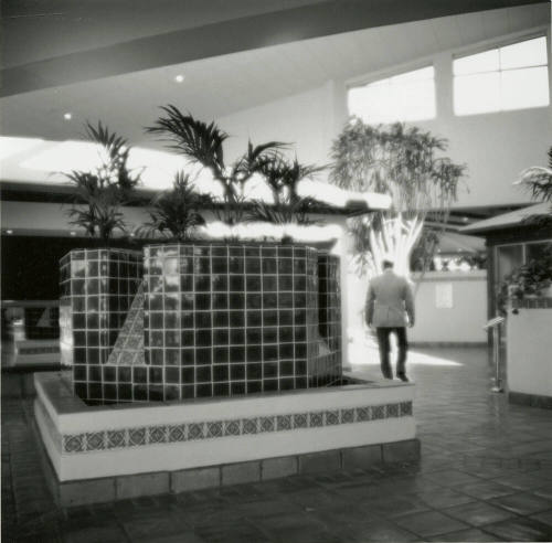 Man walking through interior of building with tile fountain