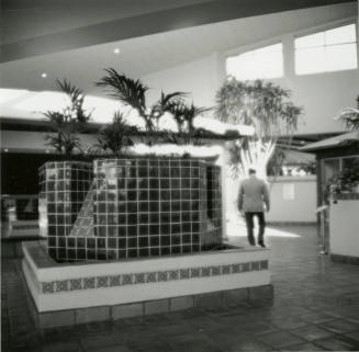 Man walking through interior of building with tile fountain