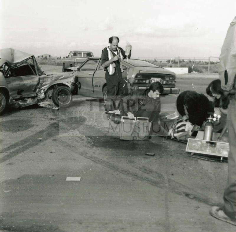 Paramedics attend to injured woman at the scene of a car collision