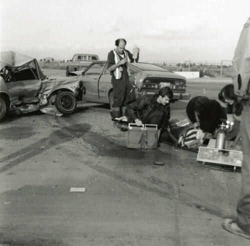Paramedics attend to injured woman at the scene of a car collision