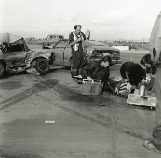 Paramedics attend to injured woman at the scene of a car collision