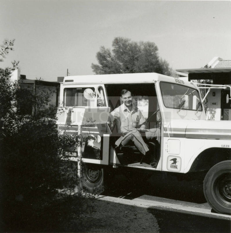 Unidentified postman puts mail in a mailbox