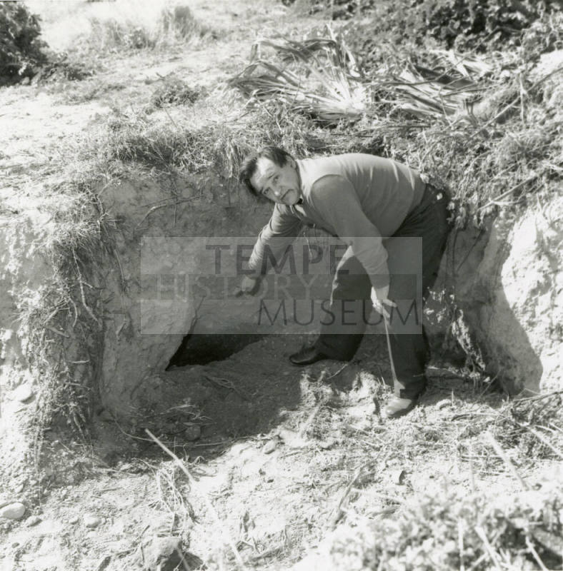 Unknown man pointing to a hole in the ground