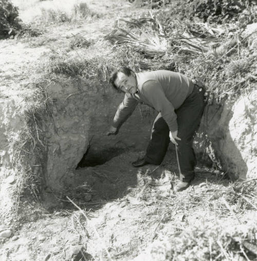 Unknown man pointing to a hole in the ground