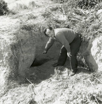 Unknown man pointing to a hole in the ground