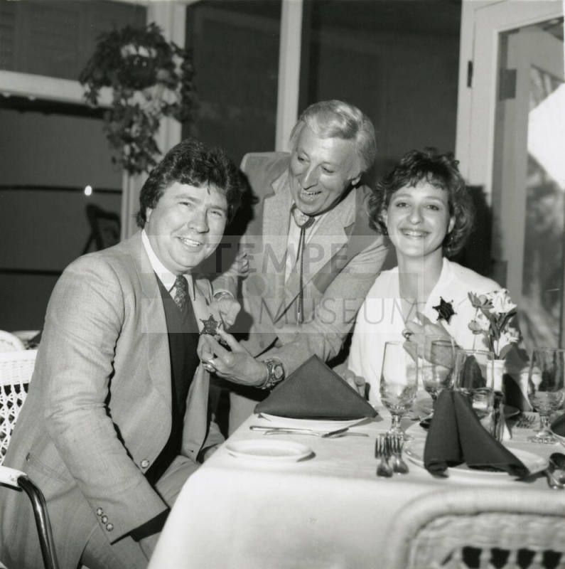 Young woman and two men, one being given a sheriff's badge