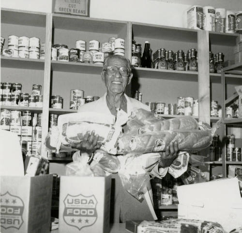 Man holds loaves of bread in a grocery store