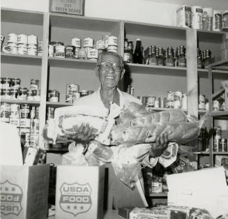 Man holds loaves of bread in a grocery store