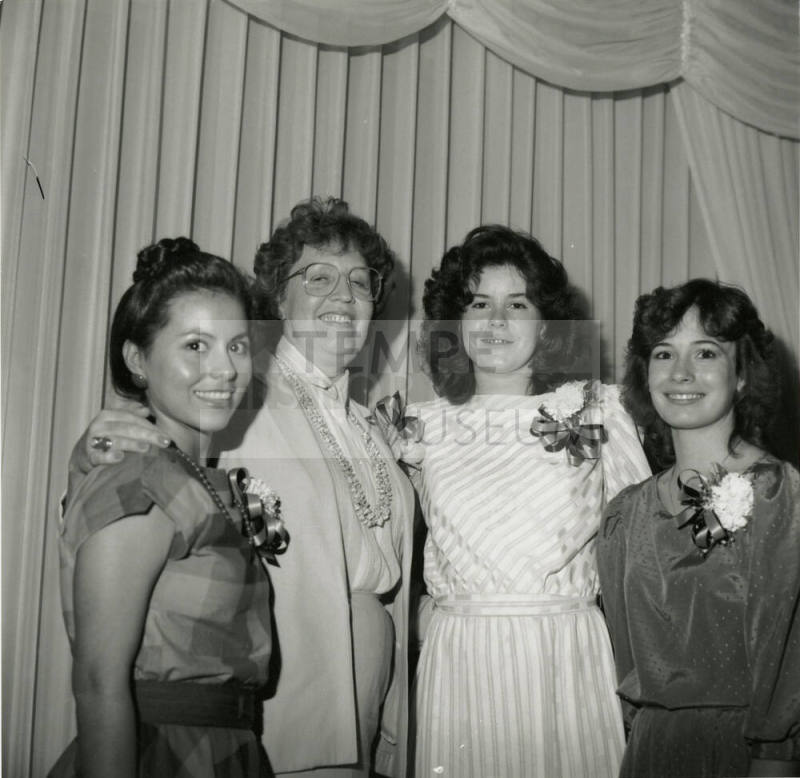 3 young women and an older woman in front of a curtain
