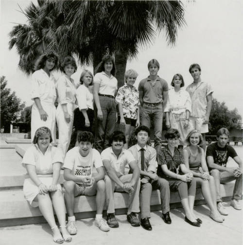 Group of youths posing outside in front of a palm tree