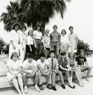 Group of youths posing outside in front of a palm tree