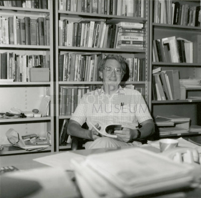 Unidentified man at desk amid bookcases
