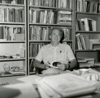 Unidentified man at desk amid bookcases