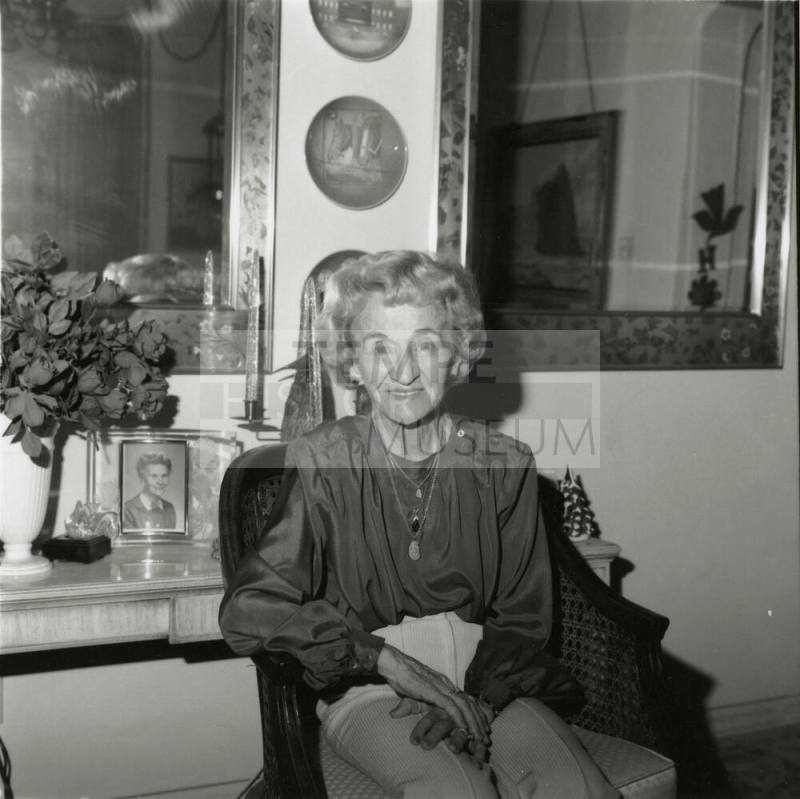 Elderly woman sits inside her home